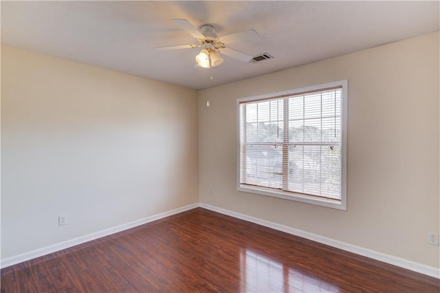 spare room with ceiling fan, baseboards, visible vents, and dark wood finished floors