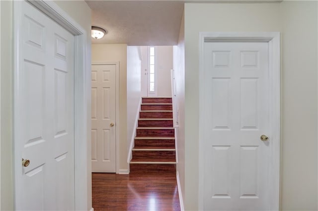 hall with dark wood-type flooring, stairway, and baseboards