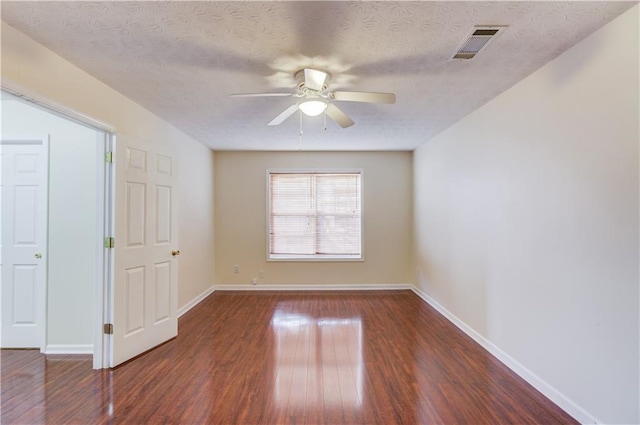 unfurnished room featuring dark wood-style floors, ceiling fan, visible vents, and baseboards