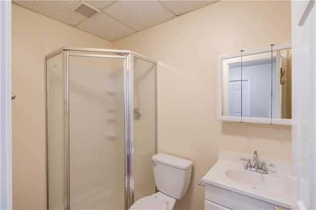 full bathroom with visible vents, toilet, a shower stall, vanity, and a drop ceiling