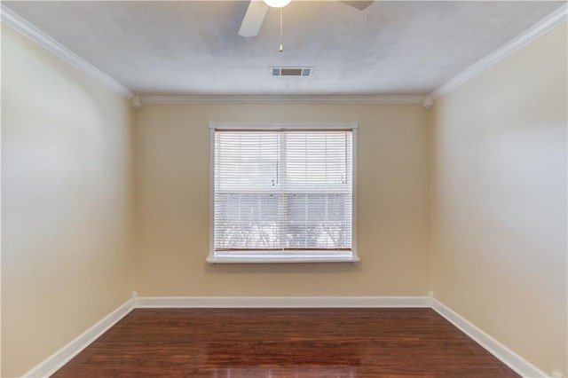 empty room with dark wood-style flooring, visible vents, crown molding, and baseboards