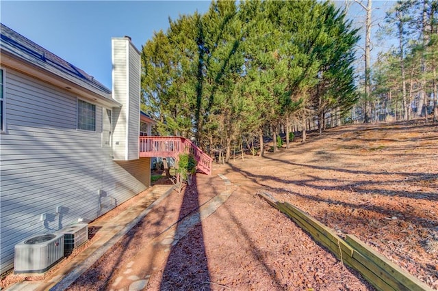 view of yard featuring central air condition unit and a deck