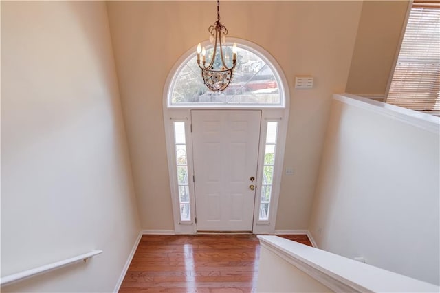 entryway with a chandelier, baseboards, and light wood finished floors