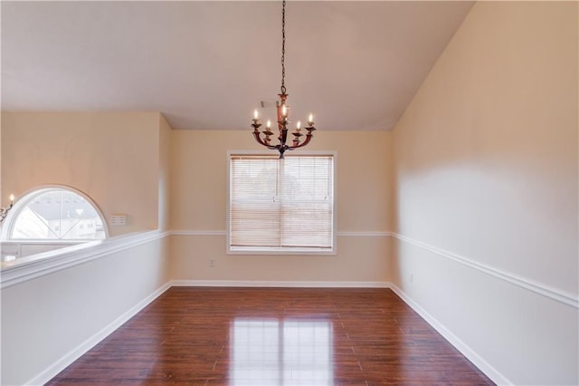 spare room with baseboards, dark wood finished floors, lofted ceiling, and an inviting chandelier