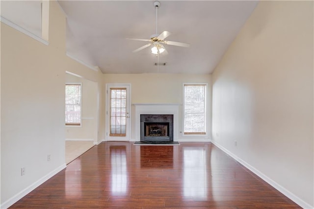 unfurnished living room with ceiling fan, lofted ceiling, a fireplace, visible vents, and dark wood finished floors