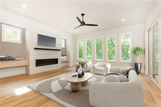 living room with a healthy amount of sunlight, a large fireplace, and light wood-type flooring