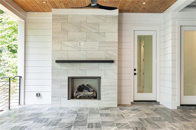 unfurnished living room with a fireplace, ceiling fan, and wood walls