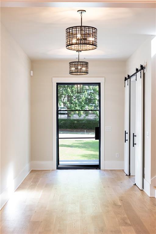 entrance foyer featuring a barn door, light hardwood / wood-style flooring, and a notable chandelier