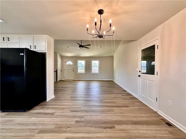 kitchen with white cabinets, ceiling fan with notable chandelier, light hardwood / wood-style flooring, and black fridge