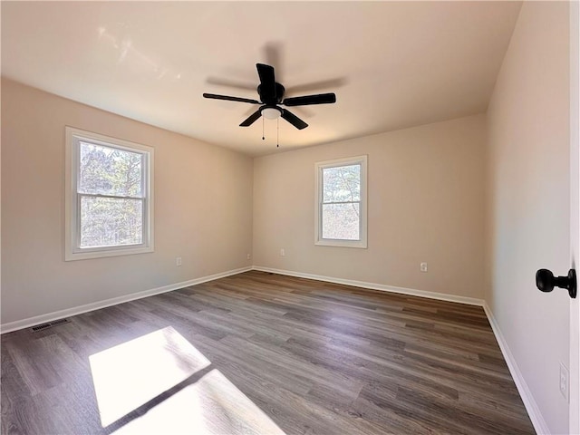 spare room featuring plenty of natural light, ceiling fan, and dark hardwood / wood-style flooring