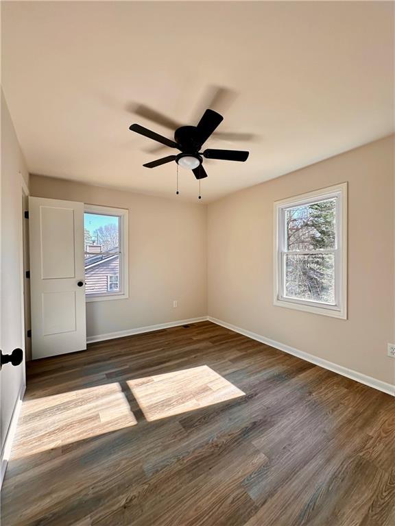 spare room with a wealth of natural light, ceiling fan, and dark hardwood / wood-style floors