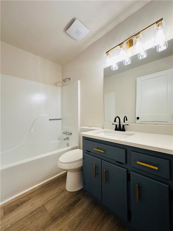 full bathroom featuring shower / bathing tub combination, hardwood / wood-style floors, vanity, and toilet