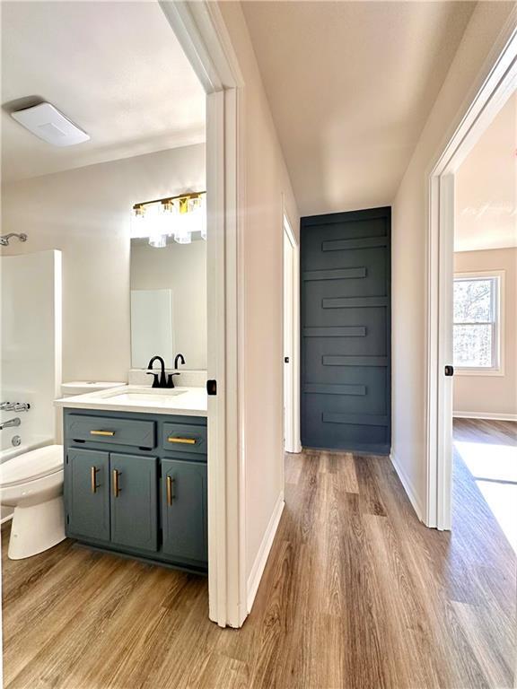 full bathroom featuring hardwood / wood-style floors, vanity, toilet, and bathing tub / shower combination