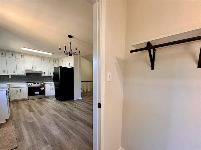 kitchen featuring white cabinetry, stainless steel electric range oven, an inviting chandelier, tasteful backsplash, and black fridge