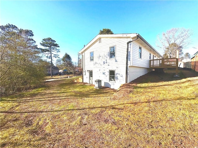 rear view of property featuring central air condition unit, a deck, and a lawn