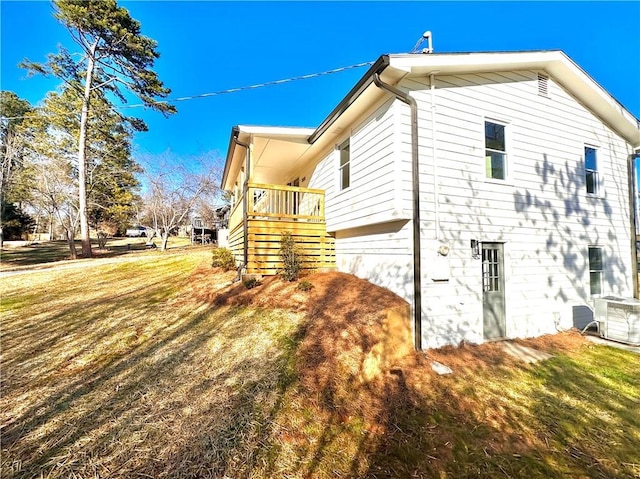 view of home's exterior featuring a lawn, a wooden deck, and central AC unit