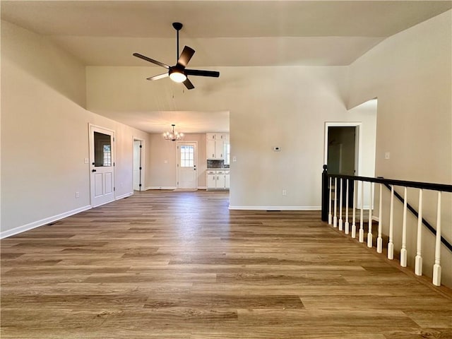 unfurnished living room featuring hardwood / wood-style floors and ceiling fan with notable chandelier