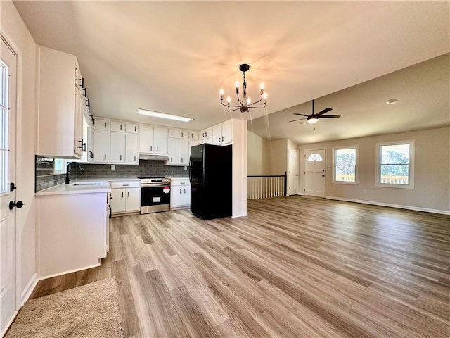 kitchen with electric stove, black fridge, white cabinets, and decorative backsplash