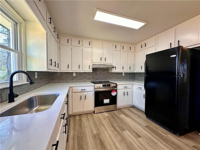 kitchen featuring white cabinets, black fridge, sink, light hardwood / wood-style flooring, and range with electric stovetop