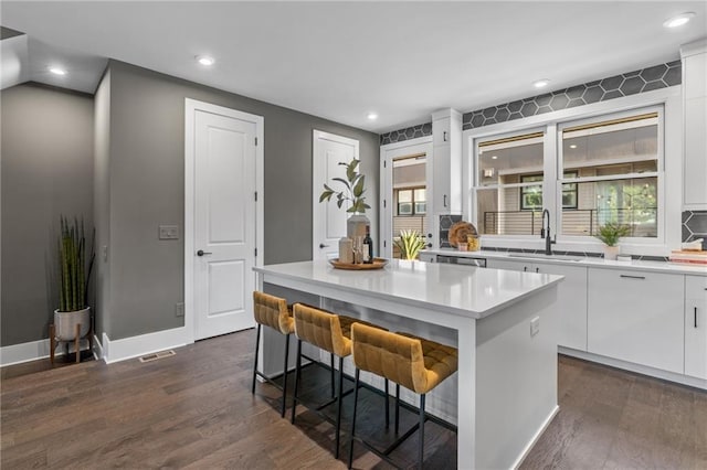 kitchen with a kitchen breakfast bar, a center island, white cabinetry, and sink