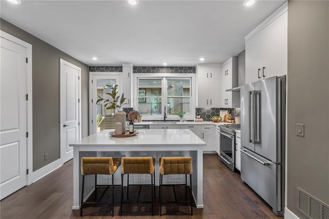 kitchen featuring a kitchen bar, premium appliances, white cabinets, and a kitchen island