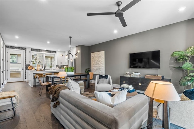 living room with ceiling fan with notable chandelier and dark hardwood / wood-style floors