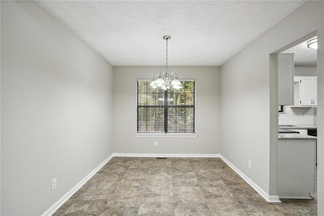 unfurnished dining area with a textured ceiling and a notable chandelier