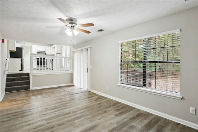 unfurnished living room featuring ceiling fan, wood-type flooring, and a textured ceiling