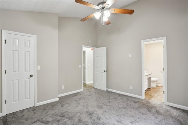 unfurnished bedroom featuring ensuite bathroom, high vaulted ceiling, light carpet, and ceiling fan