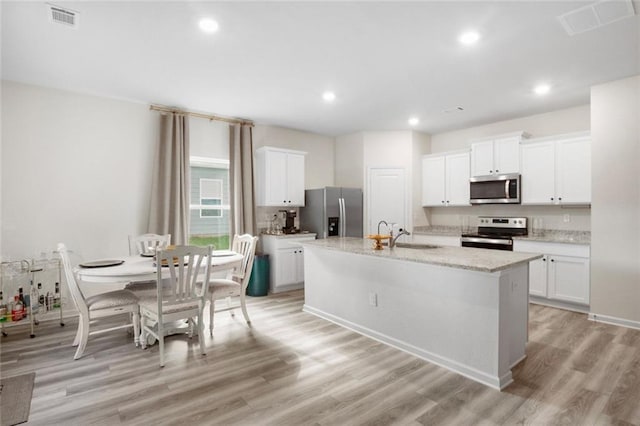 217 Limestone Cir, Conyers, GA 30013 - kitchen with appliances with stainless steel finishes, a center island with sink, light wood-style floors, white cabinetry, and recessed lighting