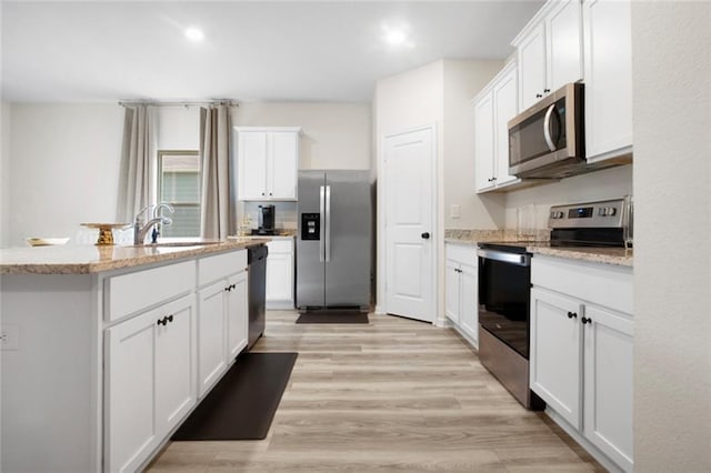 217 Limestone Cir, Conyers, GA 30013 - kitchen featuring stainless steel appliances, white cabinetry, a sink, a center island with sink, and light wood finished floors