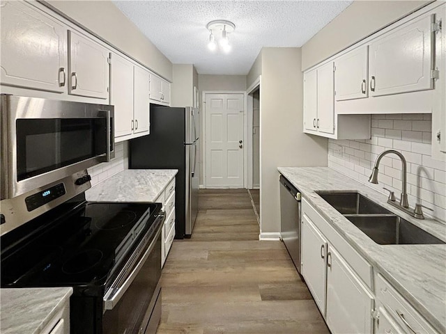 2992 Parc Lorraine, Lithonia, GA 30038 - kitchen featuring stainless steel appliances, white cabinetry, a textured ceiling, light wood-type flooring, and decorative backsplash