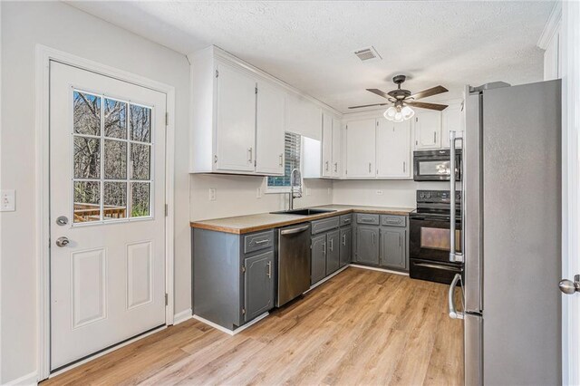 kitchen with gray cabinets, black appliances, light wood-style flooring, and a sink