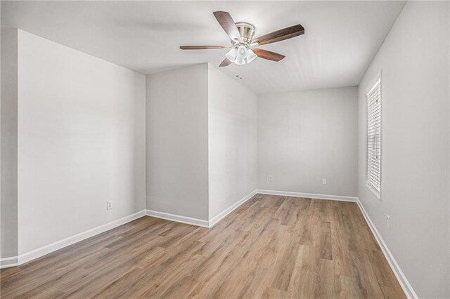 spare room with baseboards, wood finished floors, and a ceiling fan