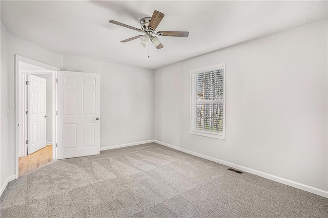 carpeted empty room with baseboards, ceiling fan, and visible vents