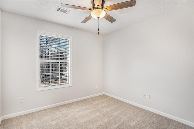 carpeted spare room with baseboards, a textured ceiling, visible vents, and ceiling fan