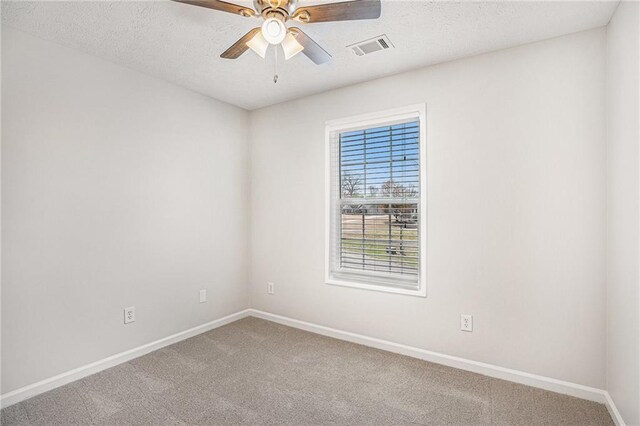 carpeted empty room with baseboards, a textured ceiling, visible vents, and a ceiling fan