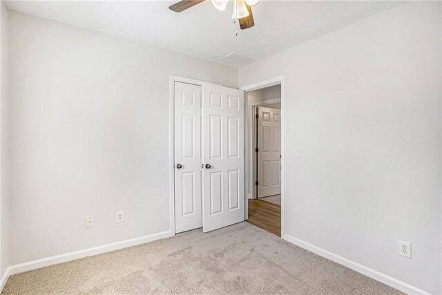 unfurnished bedroom featuring baseboards, a closet, carpet floors, and a ceiling fan
