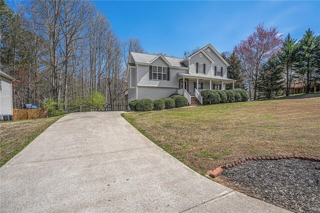 view of front of house featuring fence, a front yard, a porch, and concrete driveway