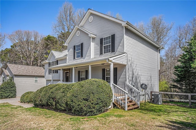 traditional home featuring a porch, a front yard, and fence