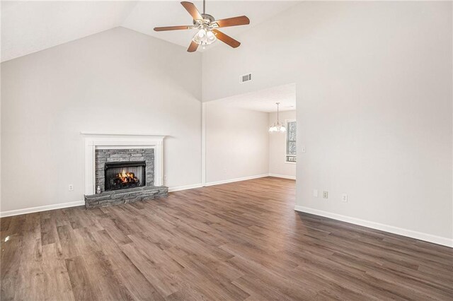 unfurnished living room featuring wood finished floors, ceiling fan with notable chandelier, a fireplace, and visible vents