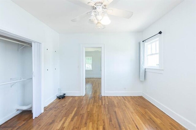 unfurnished bedroom with hardwood / wood-style flooring, ceiling fan, and multiple windows