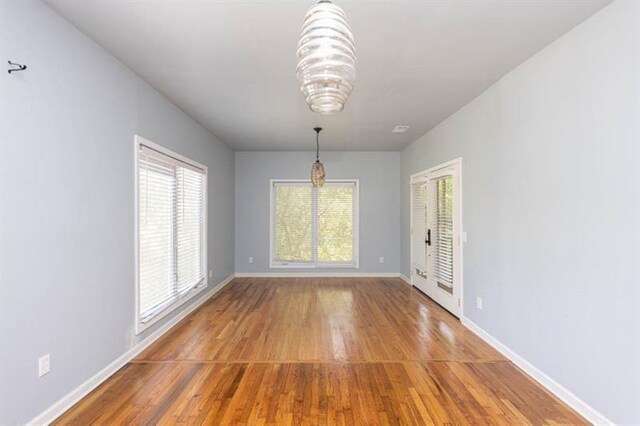 unfurnished dining area with a notable chandelier and wood-type flooring