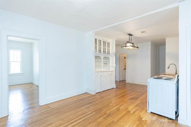 interior space with white cabinets, washer / clothes dryer, hanging light fixtures, and light hardwood / wood-style floors