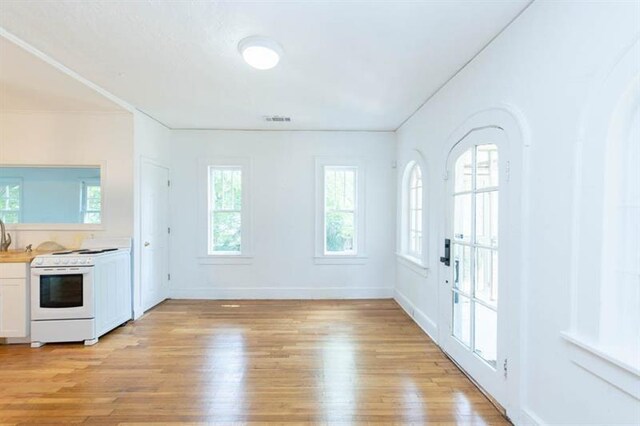 interior space featuring white cabinets, light hardwood / wood-style floors, electric stove, and a wealth of natural light