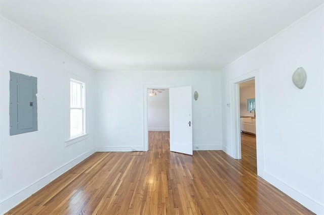 spare room with wood-type flooring, electric panel, and ceiling fan