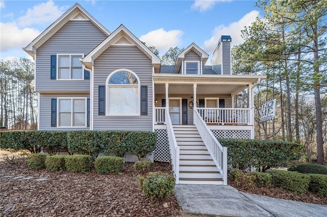 view of front of property featuring covered porch, a chimney, and stairs