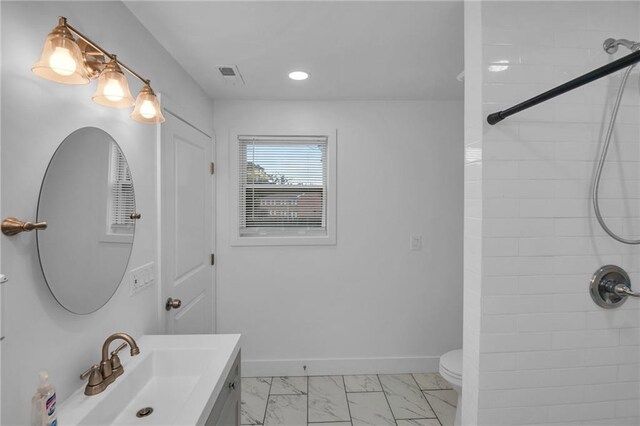 bathroom with vanity, toilet, and tiled shower