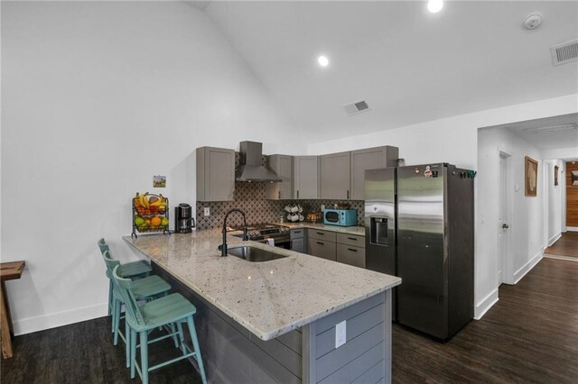 kitchen with kitchen peninsula, sink, gray cabinetry, and stainless steel refrigerator with ice dispenser