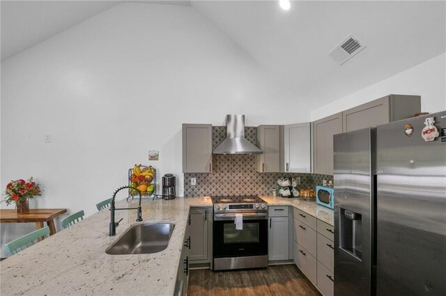 kitchen with light stone counters, sink, wall chimney exhaust hood, appliances with stainless steel finishes, and dark hardwood / wood-style floors